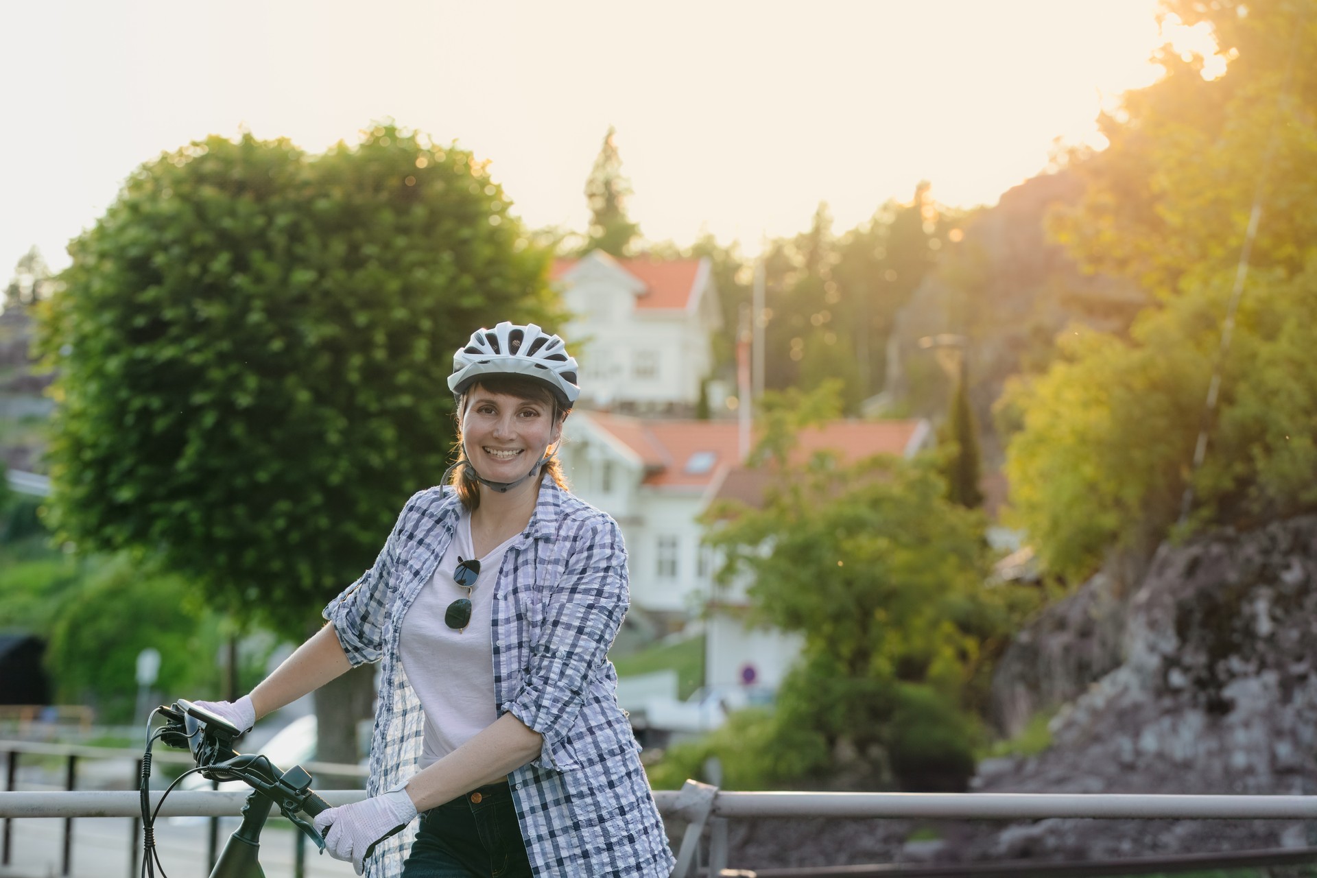 Woman in helmet  smiling standing with her bicycle  at sunset.